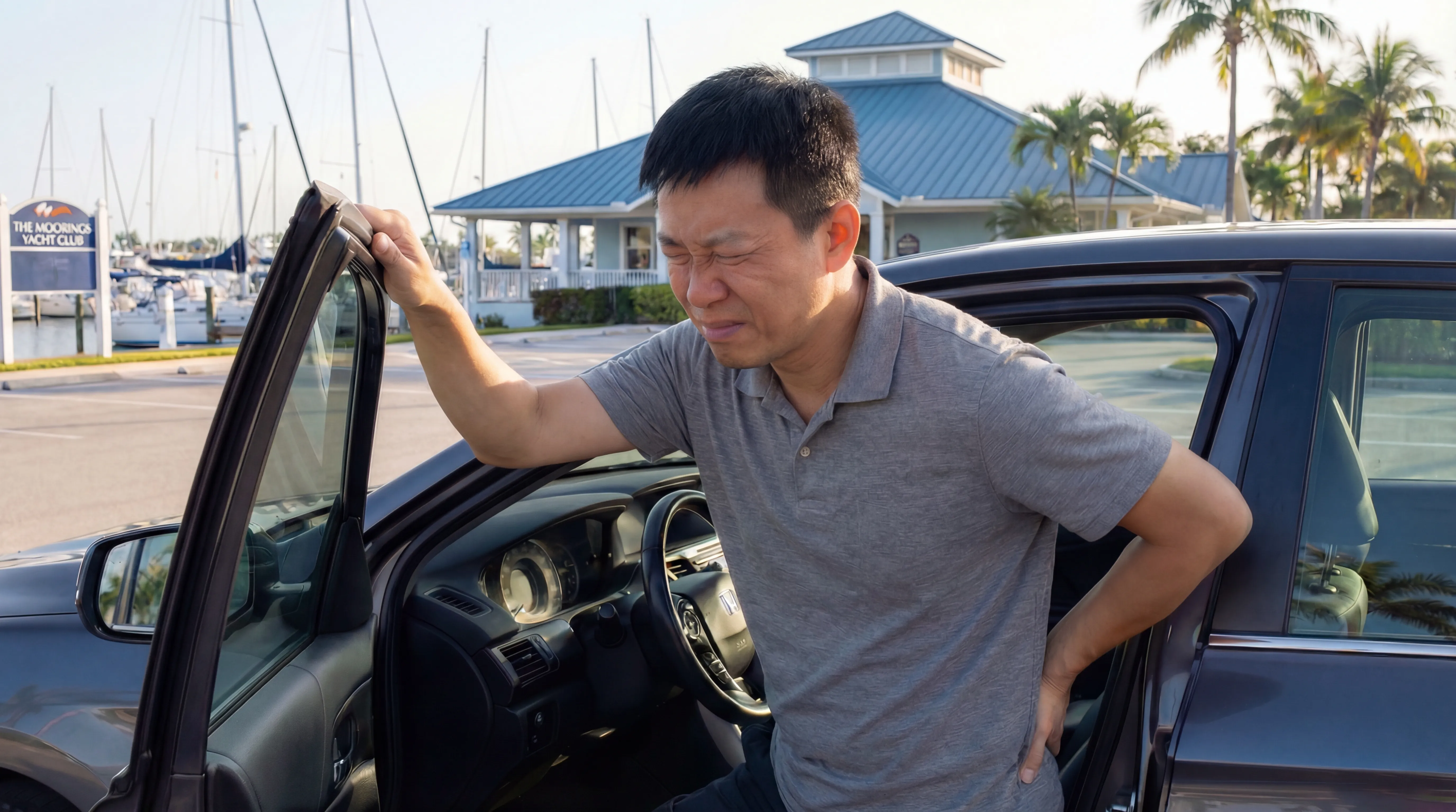 Man experiencing herniated disc back pain while getting out of his car at The Moorings marina in Naples, Florida
